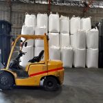 Big yellow car loader and White hemp sacks containing chemical fertilizer in the warehouse.