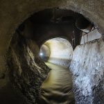 Inside underground urban sewer system. Sewage flowing in round sewer pipe