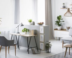 Real photo of a bright home office interior with a desk, armchair and plants